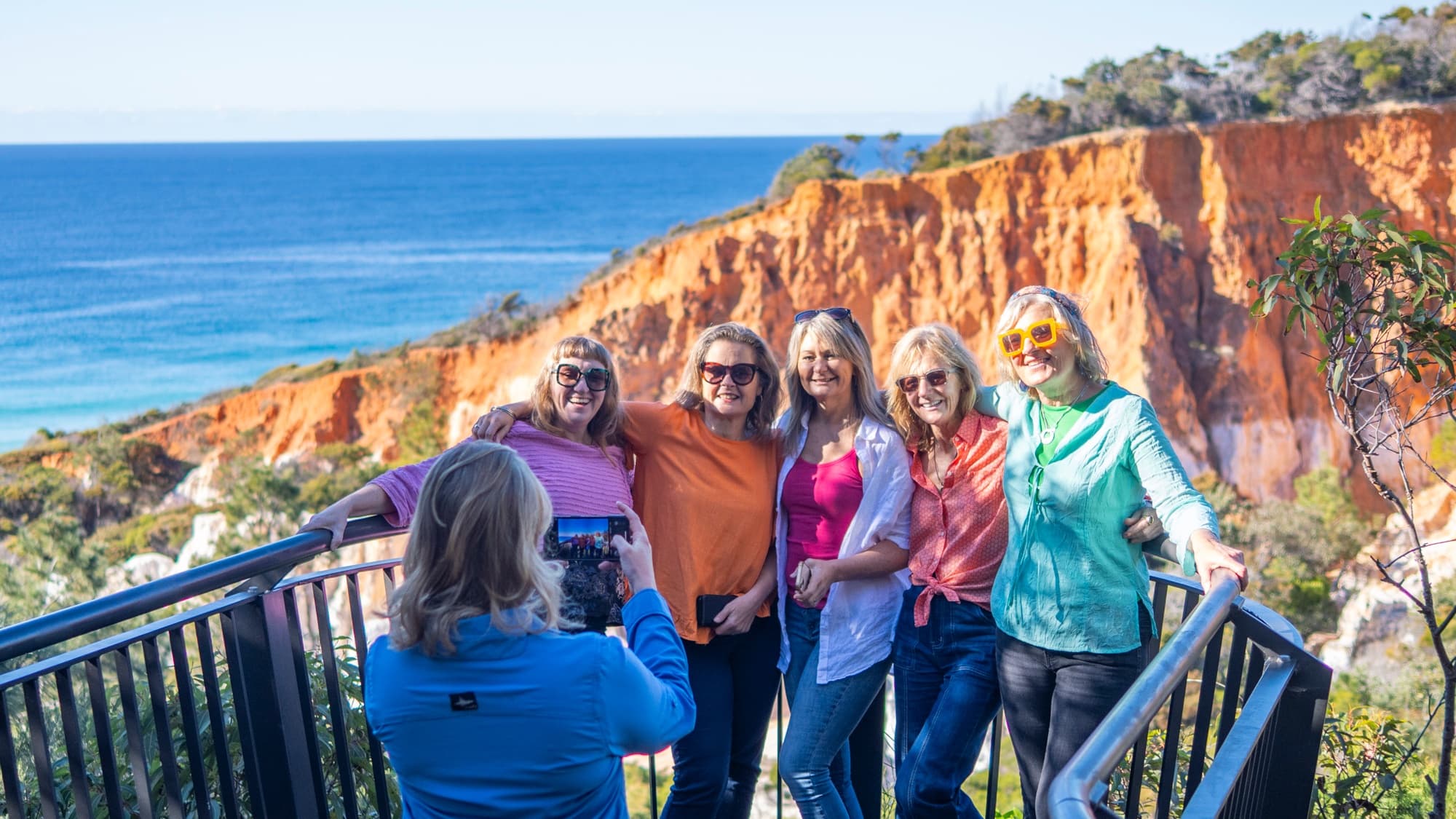 Group of hikers enjoying cliffside ocean lookout viewpoint