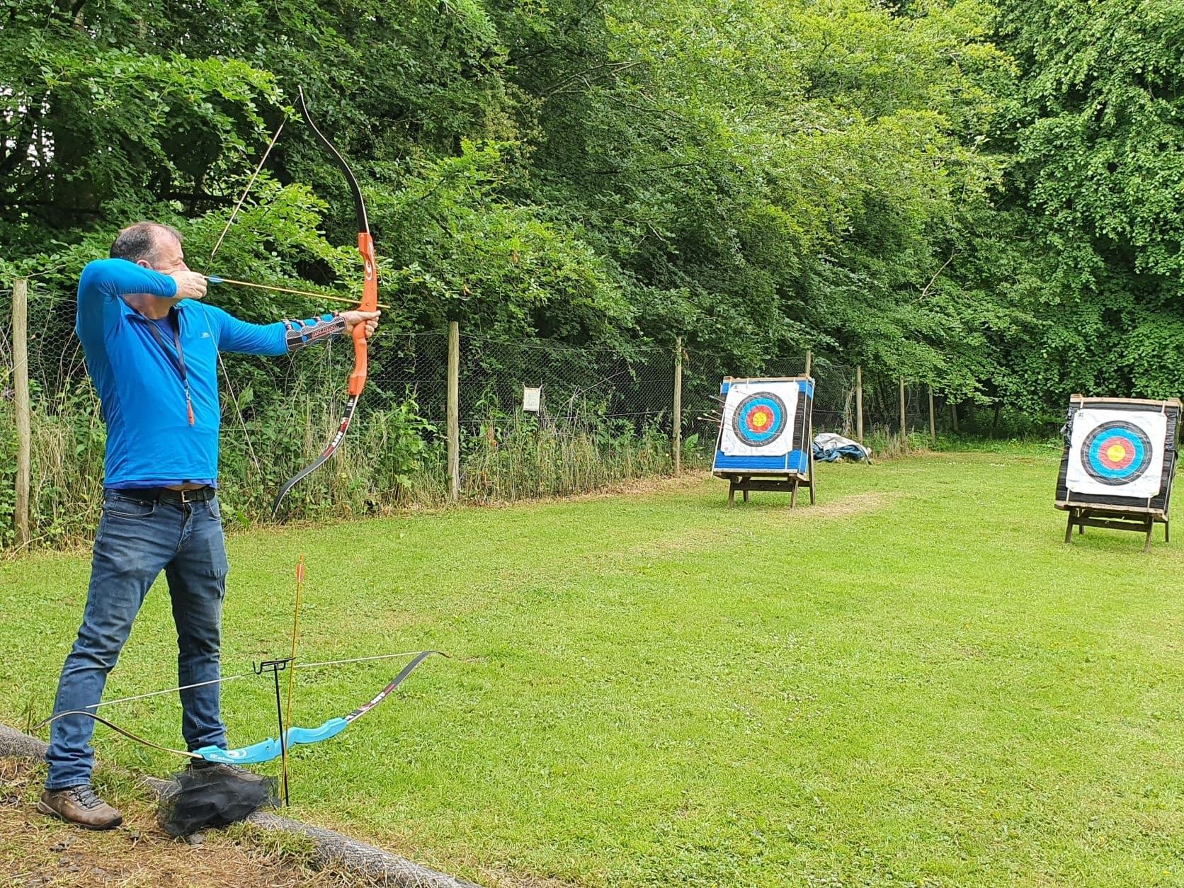 Archer aiming at targets on grassy outdoor range in woodland