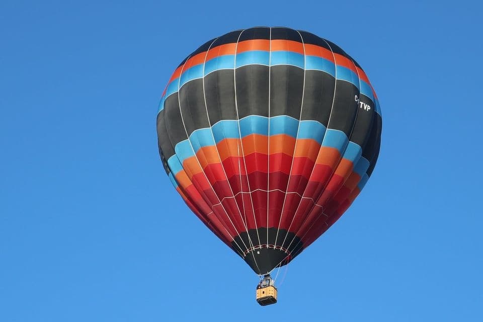 Colorful hot air balloon rising against deep blue sky, close-up