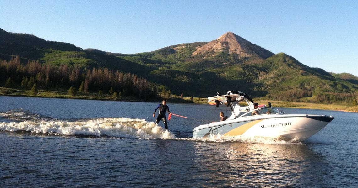 Speedboat pulling wakeboarder on Steamboat Lake at sunset