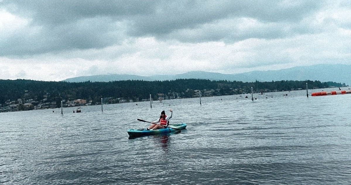 Solo kayaker paddling on open lake with distant mountains