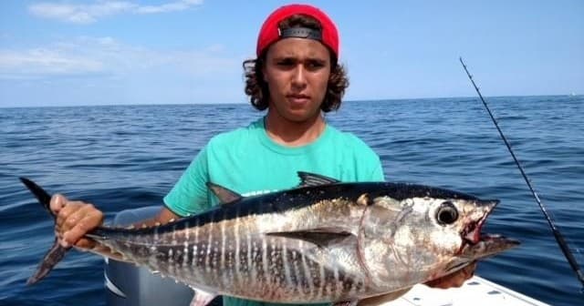 Angler displaying freshly caught tuna aboard offshore charter