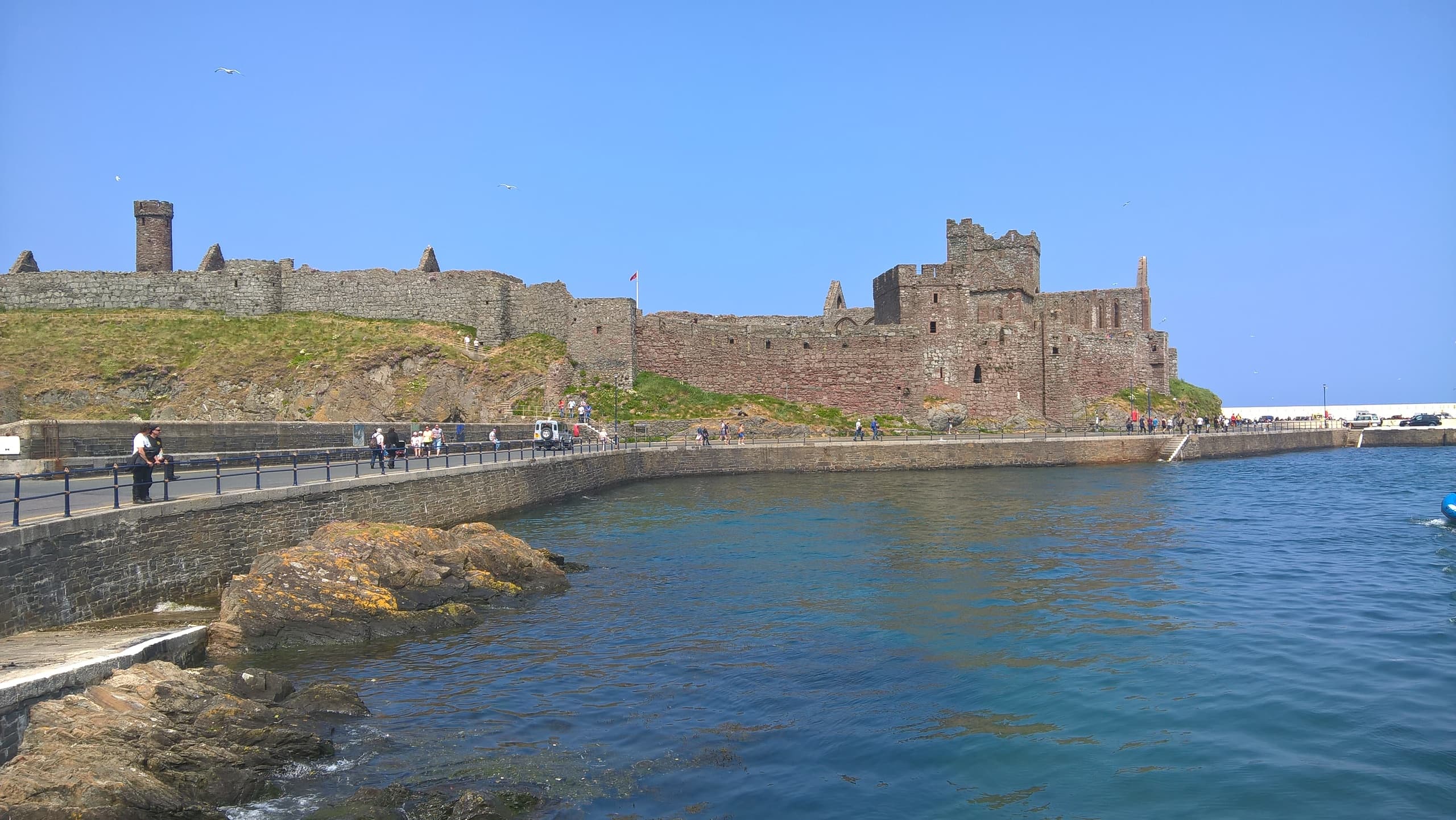 Seaside castle ruins along coastal promenade, scenic historical walk