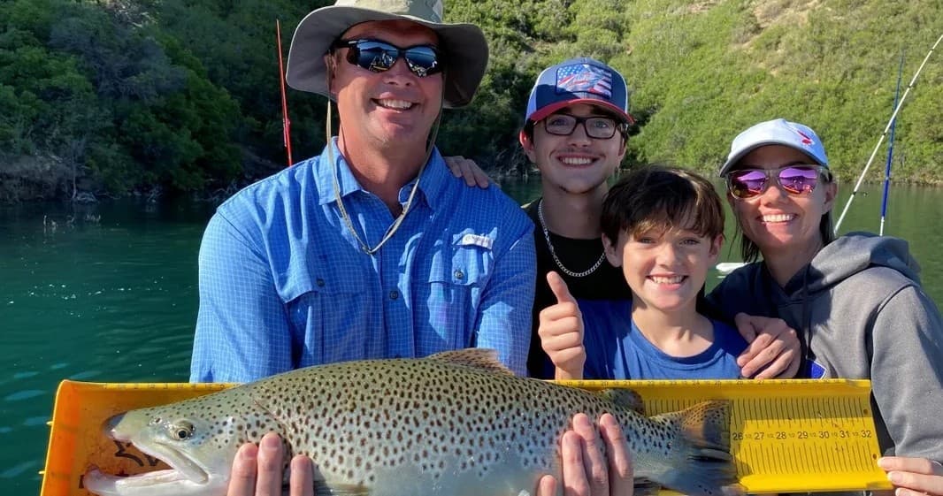 Family anglers posing with trophy brown trout on boat