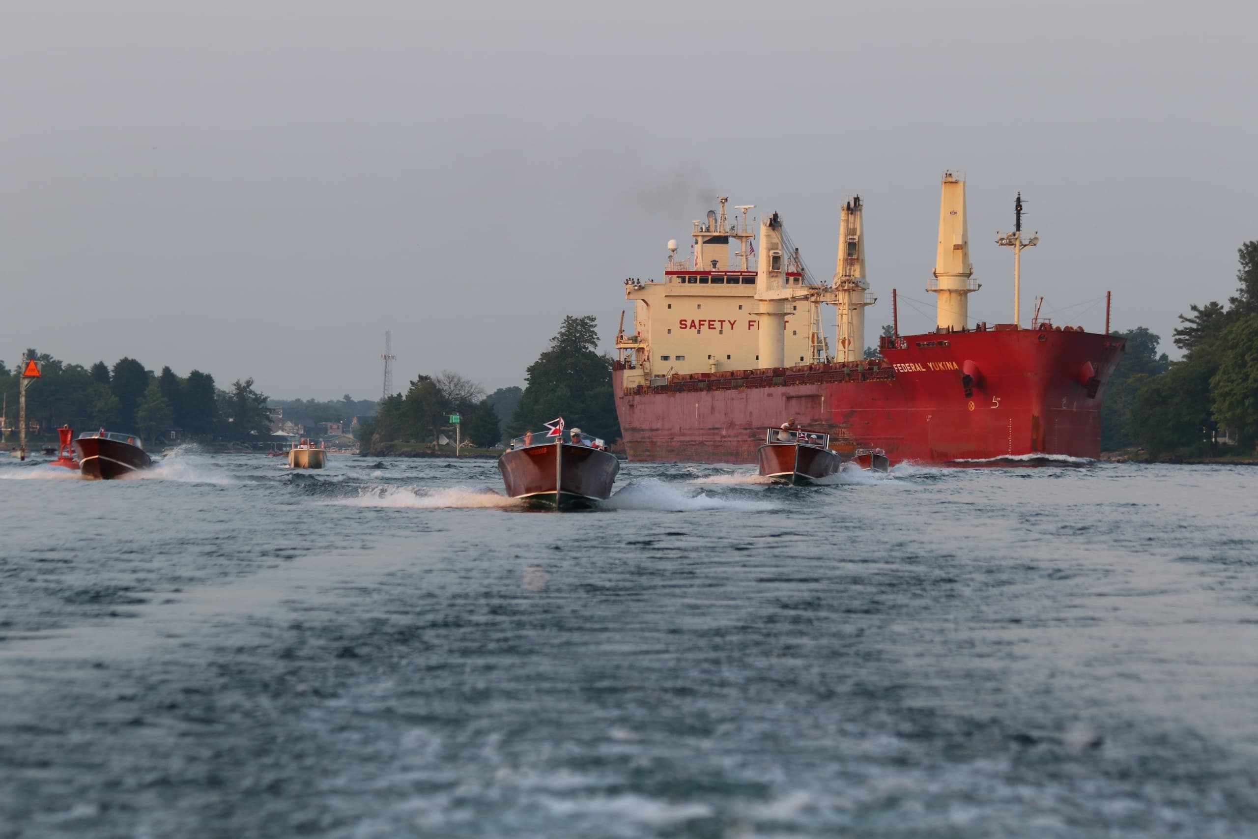 Cargo vessel and pilot boats creating wake through river