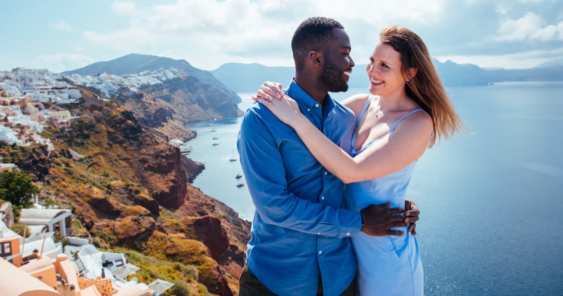 Couple embracing on coastal cliff overlooking Aegean Sea vista