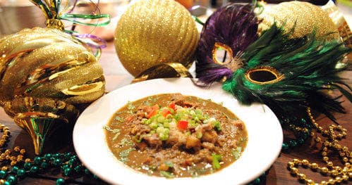Mardi Gras gumbo bowl with festive masks, beads and garnish