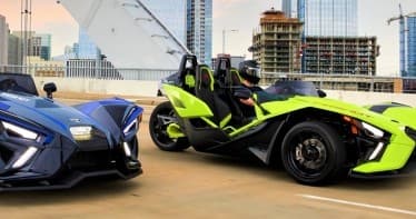Two Slingshot roadsters on urban rooftop with city skyline