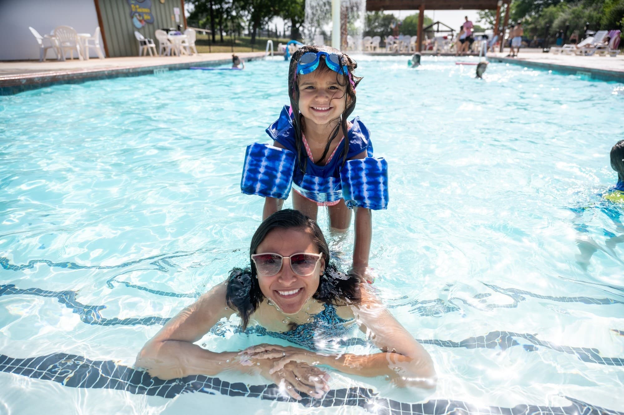Mother and daughter enjoying outdoor pool play on sunny day