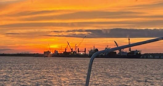 Golden harbor sunset from boat deck, evening coastal skyline view