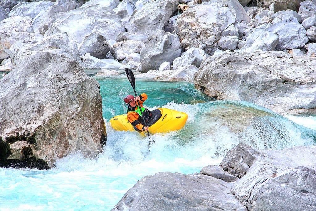 Solo kayaker navigating rocky whitewater in mountain gorge