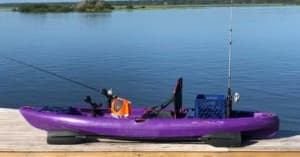 Purple fishing kayak moored at calm freshwater dock
