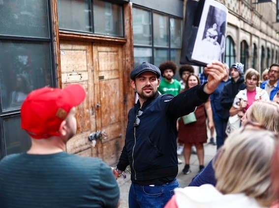 Guide leading a lively street walking tour past historic buildings