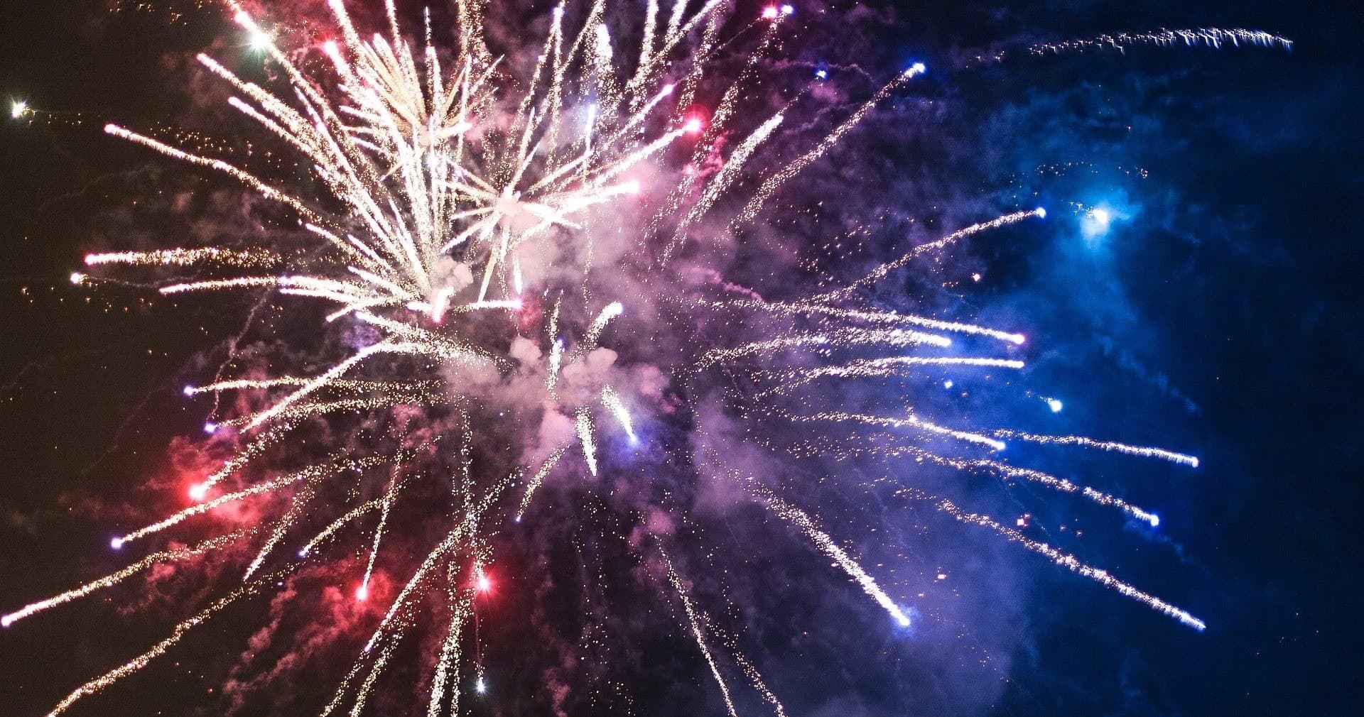 Colorful fireworks bursting over night sky at waterfront