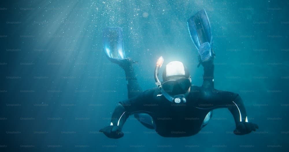 Recreational diver silhouetted with sunbeams in deep blue sea