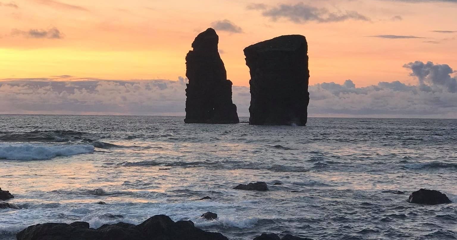 Sea stack silhouettes at sunset viewed from coastal shoreline