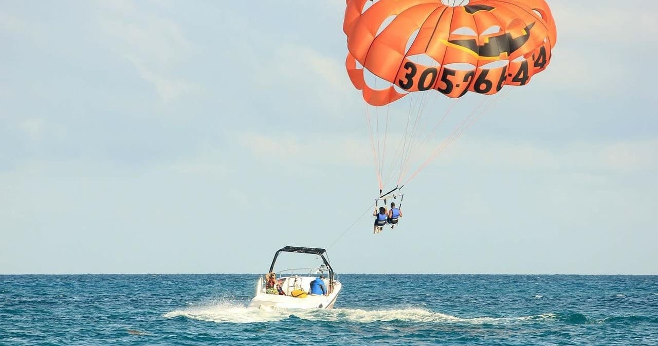 Parasailing duo soaring over turquoise ocean towed by boat