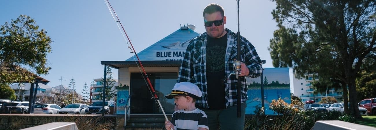 Father and child fishing from a boat near a coastal marina