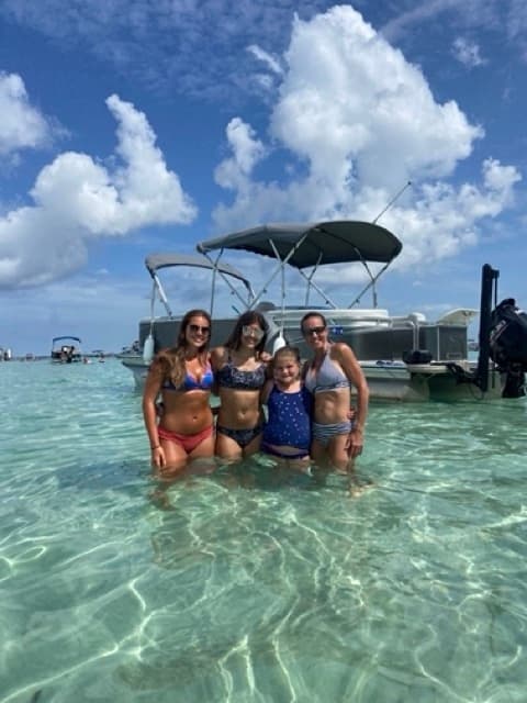 Group wading in clear turquoise water beside anchored boat