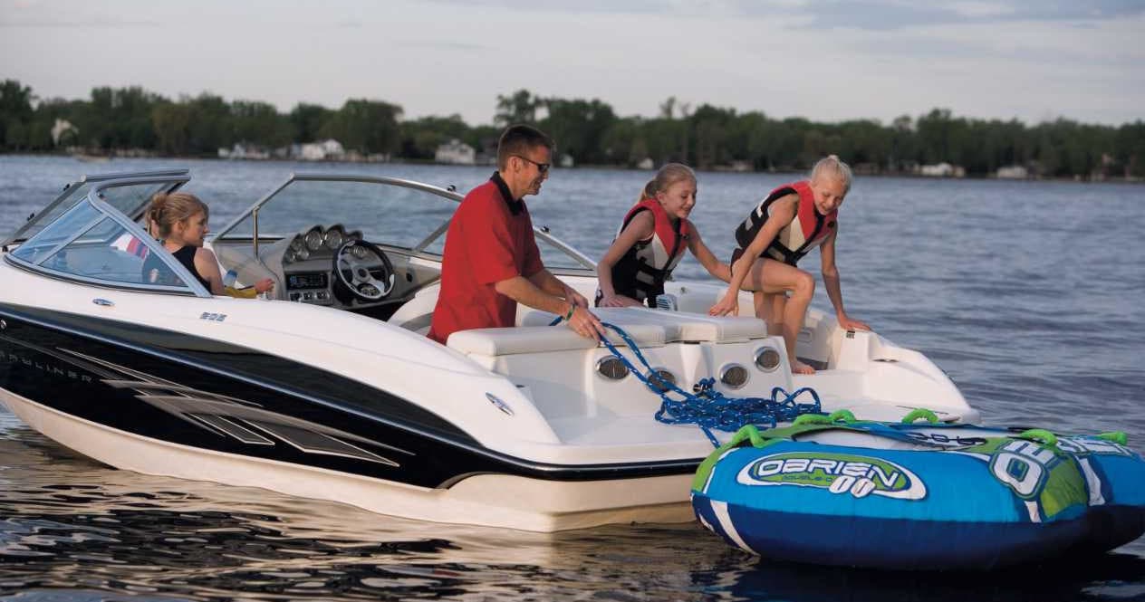 People boarding boat beside colorful towable tube on lake