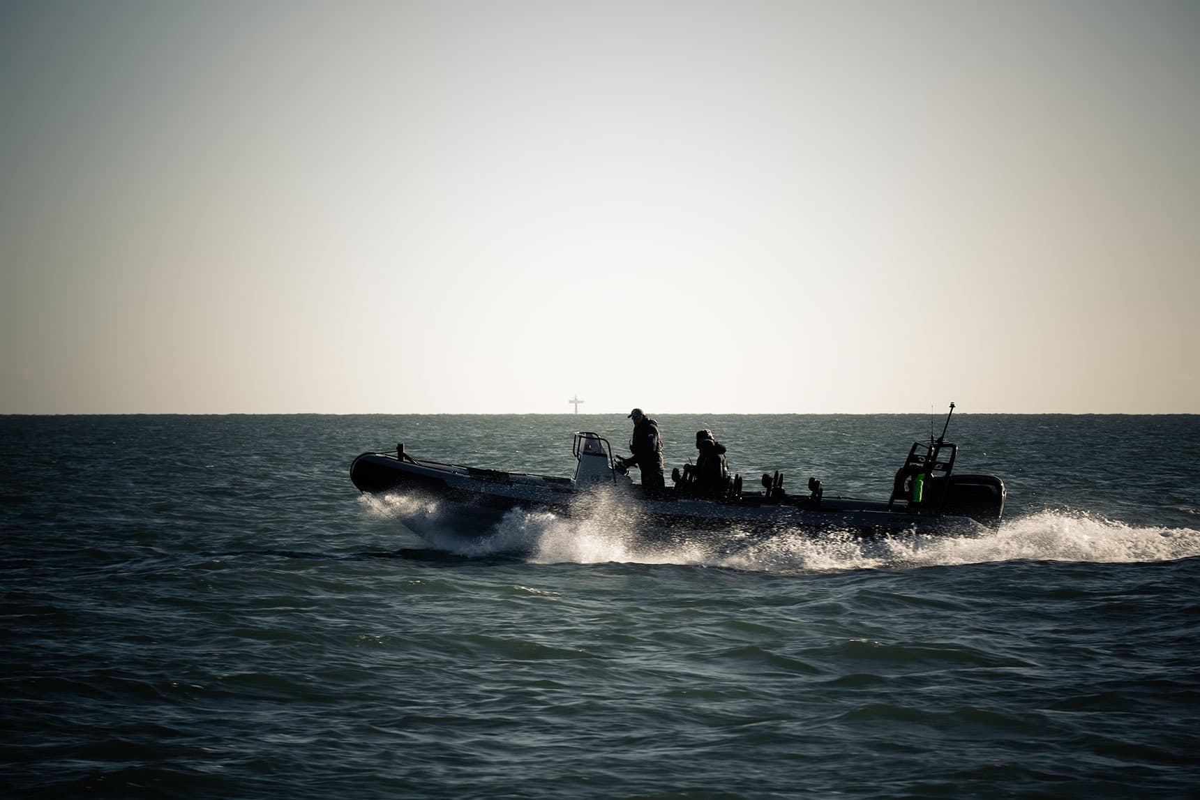 High-speed RIB boat skimming across open sea at dusk