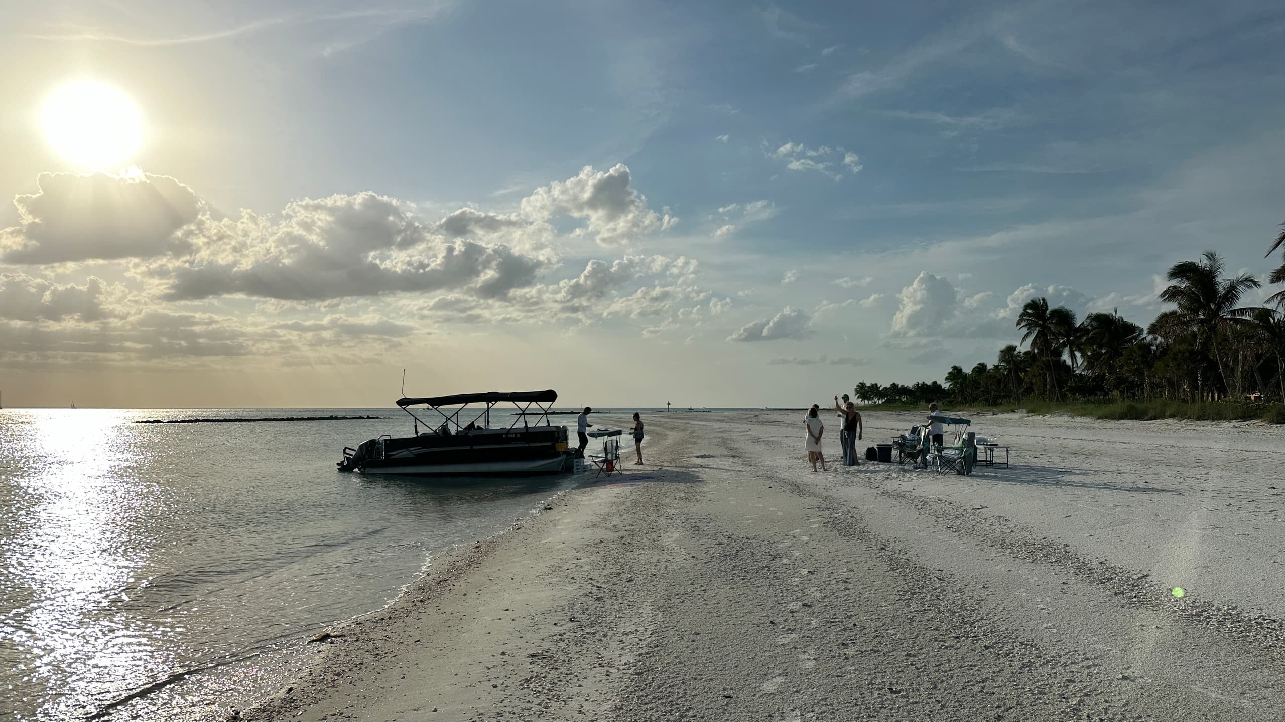 Sunset sandbar with anchored boat and beachgoers
