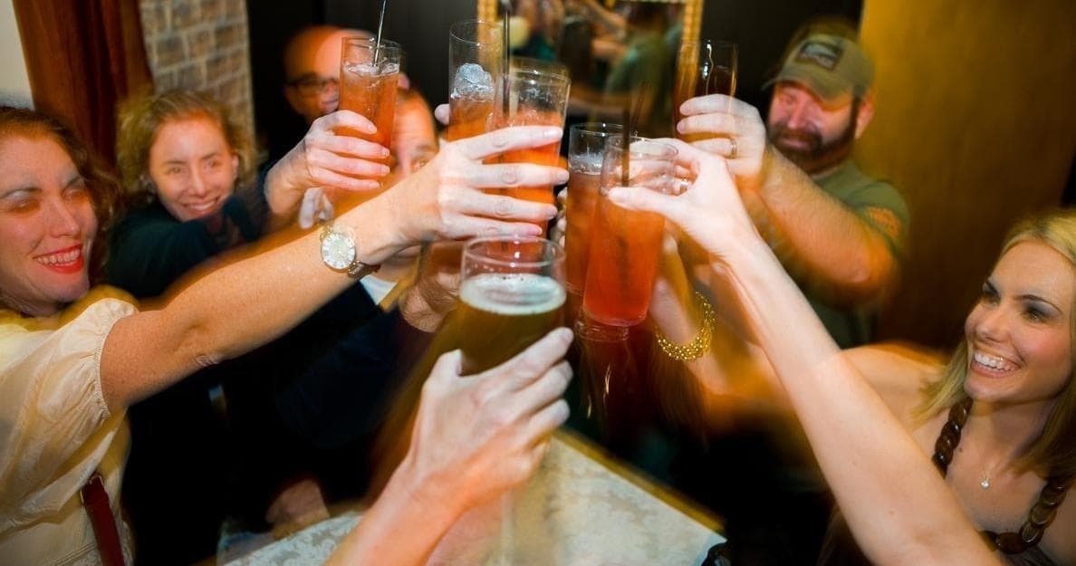 Friends toasting with craft beers in lively pub, group cheers