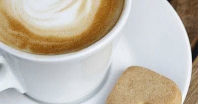 Cappuccino cup with biscuit on wooden table at café