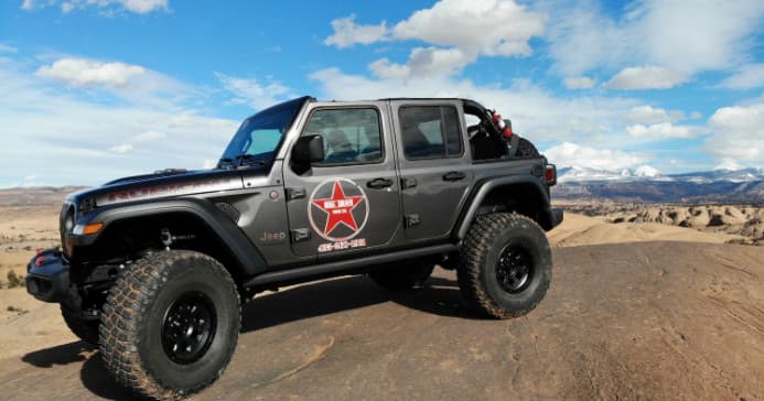 Jeep off-roading on desert slickrock with panoramic vista