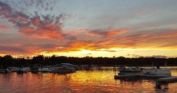 Sunset over marina with docked boats on calm lake