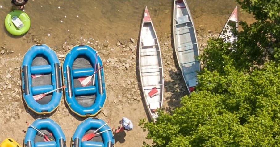 Overhead shot of rafts and canoes on sandy riverbank ready for launch