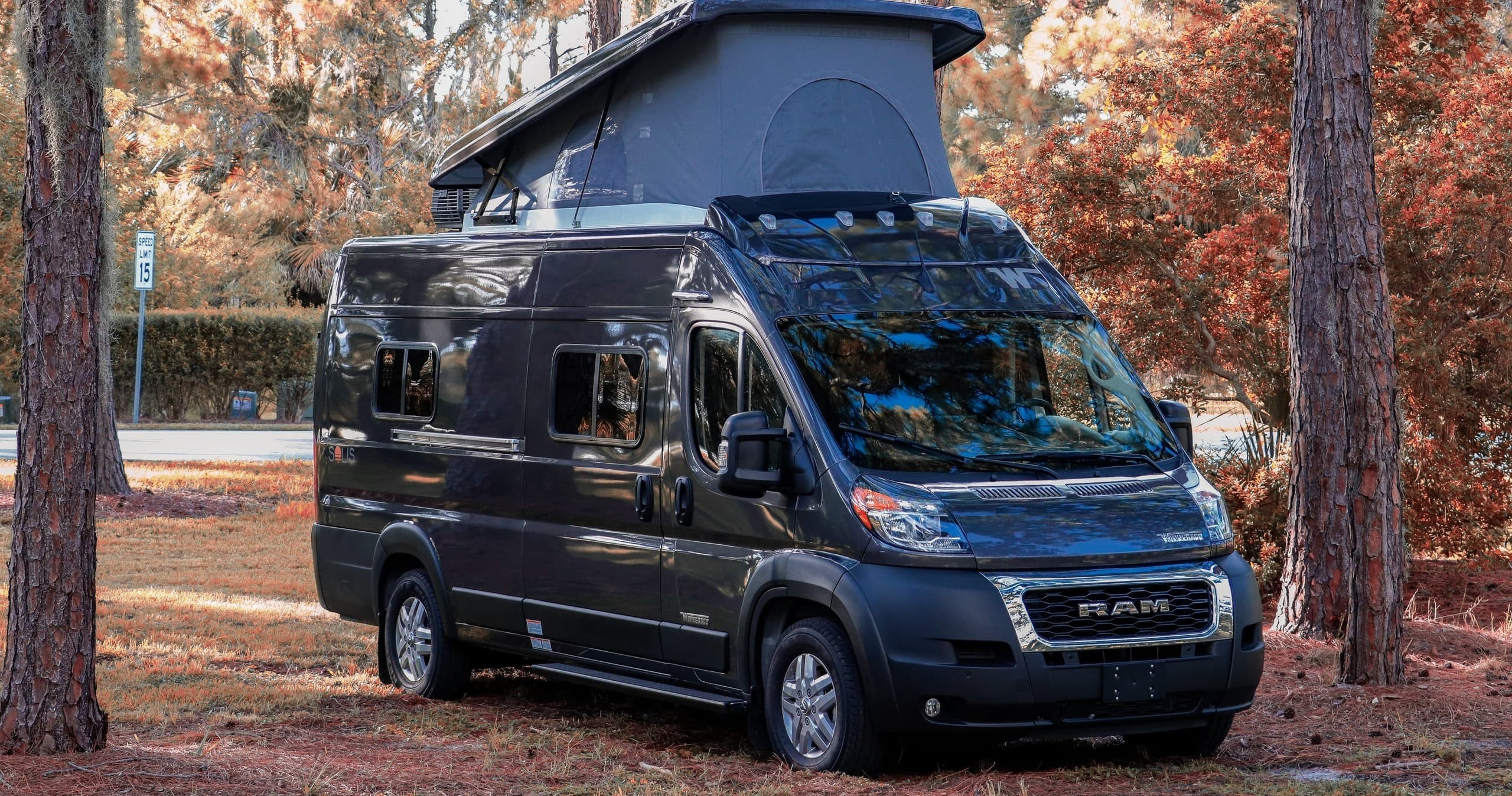 Pop-top camper van parked in pine forest campsite for camping
