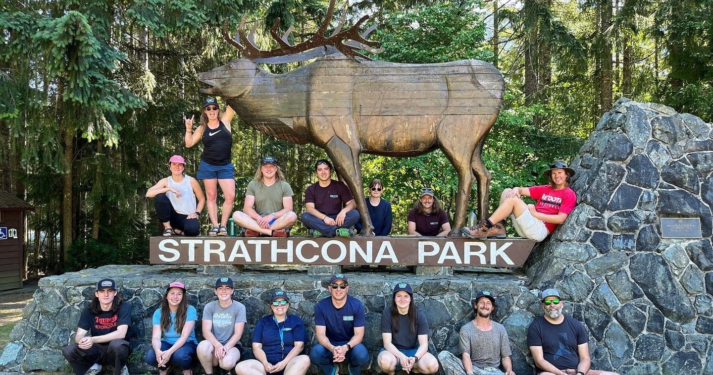 Hikers and staff posing at Strathcona Park wooden sign