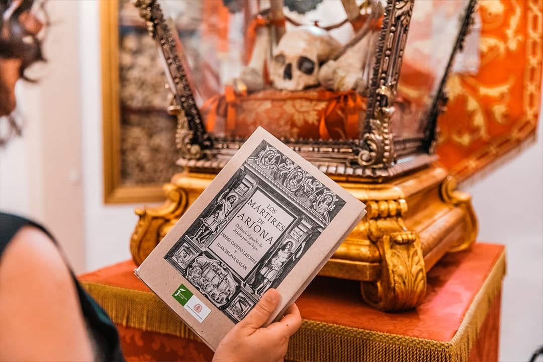 Visitor reading guidebook next to ornate reliquary display
