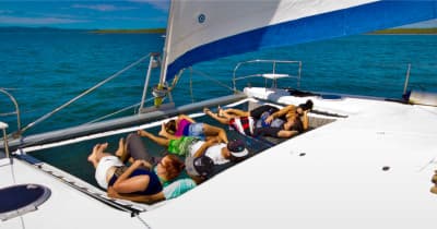 Passengers relaxing on catamaran trampoline net under sail