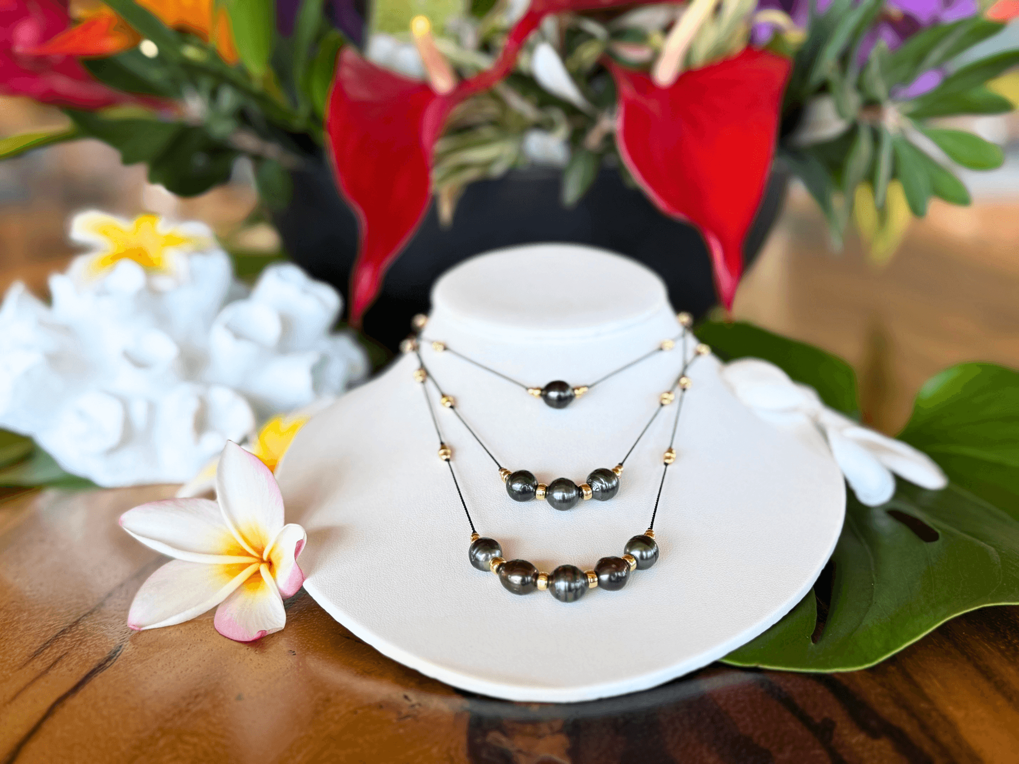 Tahitian pearl necklaces displayed on gallery table with tropical flowers