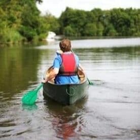 Solo canoeist paddling away on reflective river scene