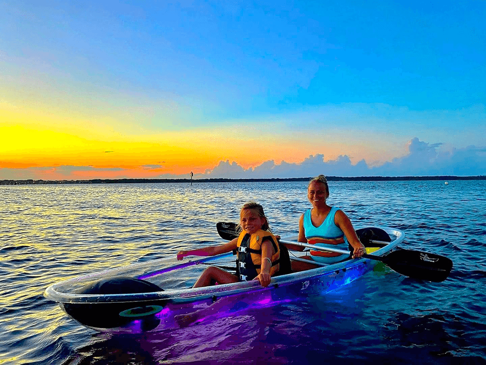 Adults paddling clear kayak at Key West sunset on bay