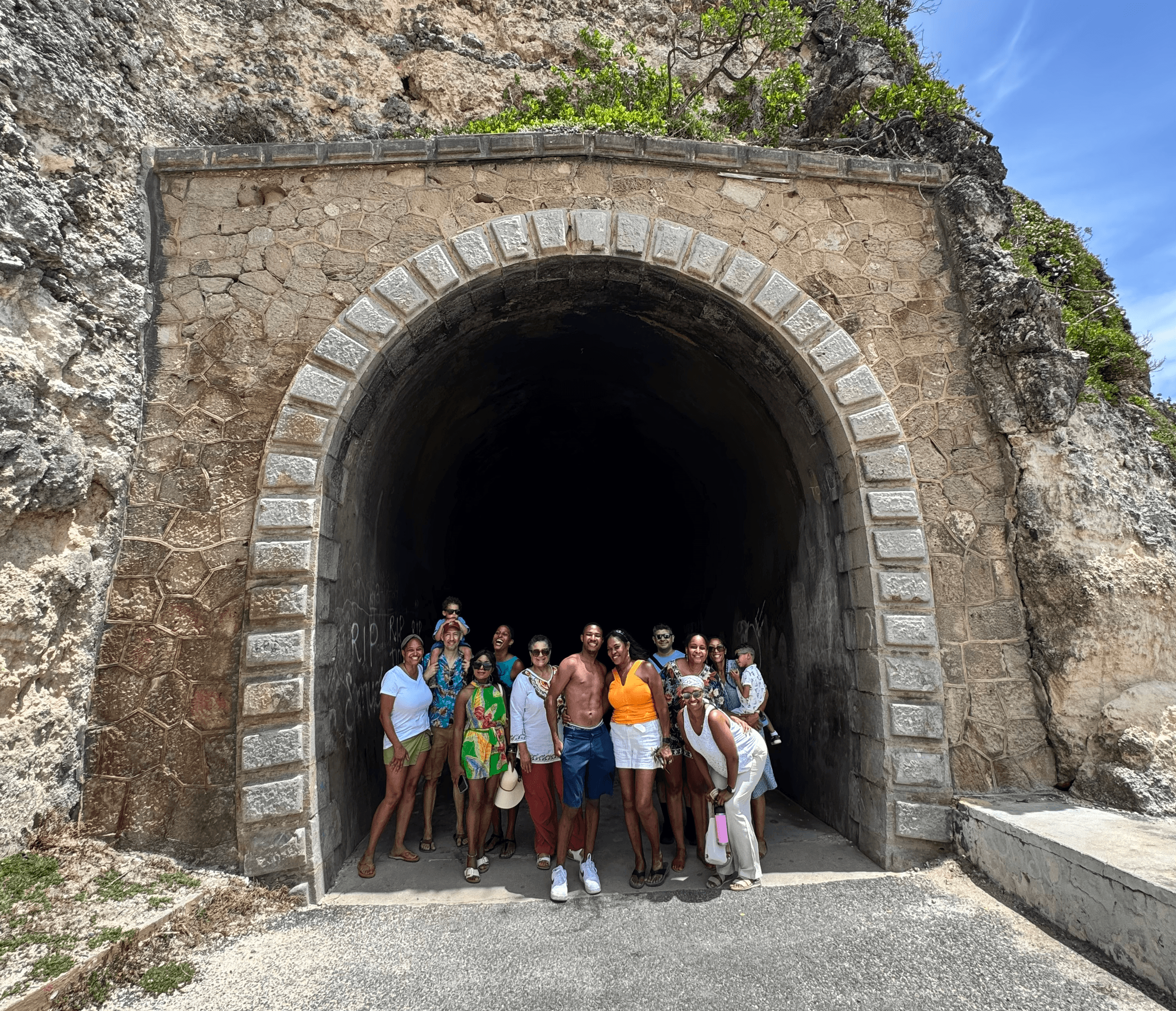 Group hiking posing at rocky tunnel entrance coastal trail