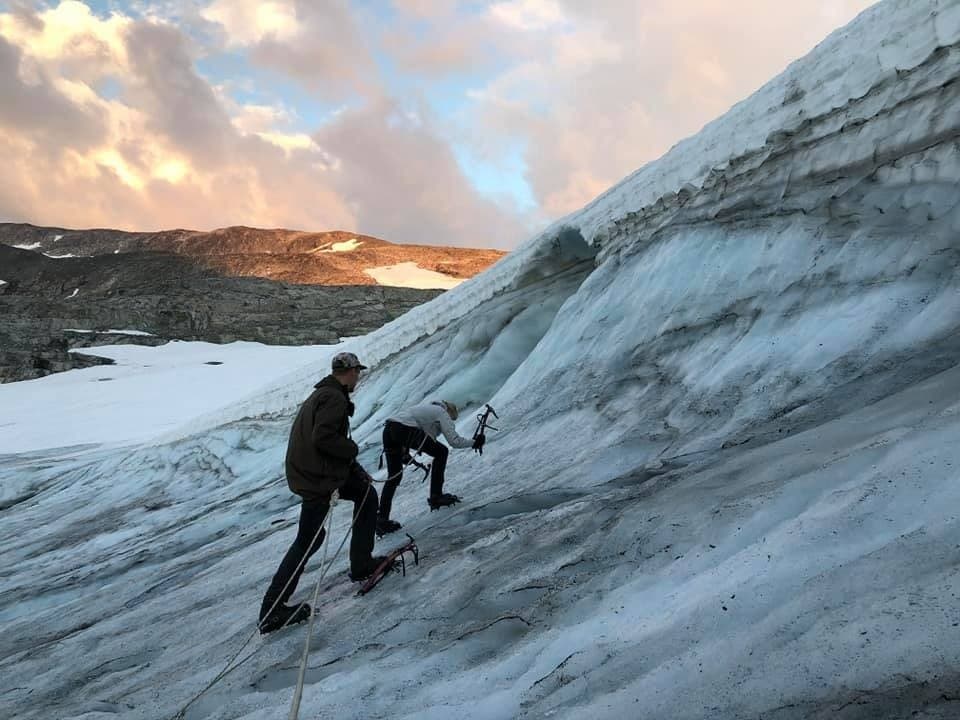 Guides leading glacier ascent across blue ice, mountain terrain