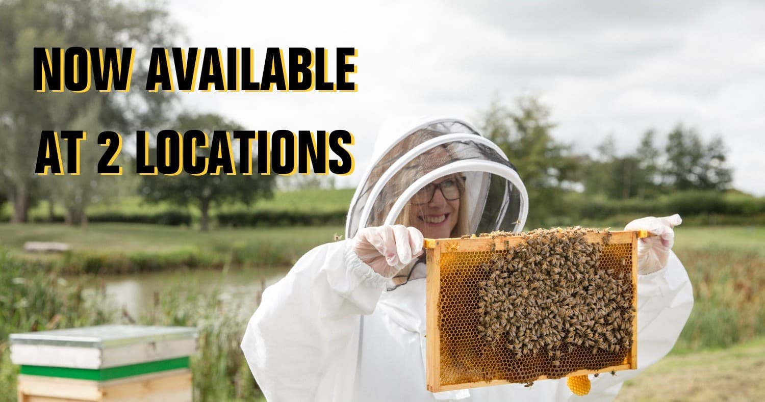 Beekeeper holding honey frame by pond at outdoor apiary