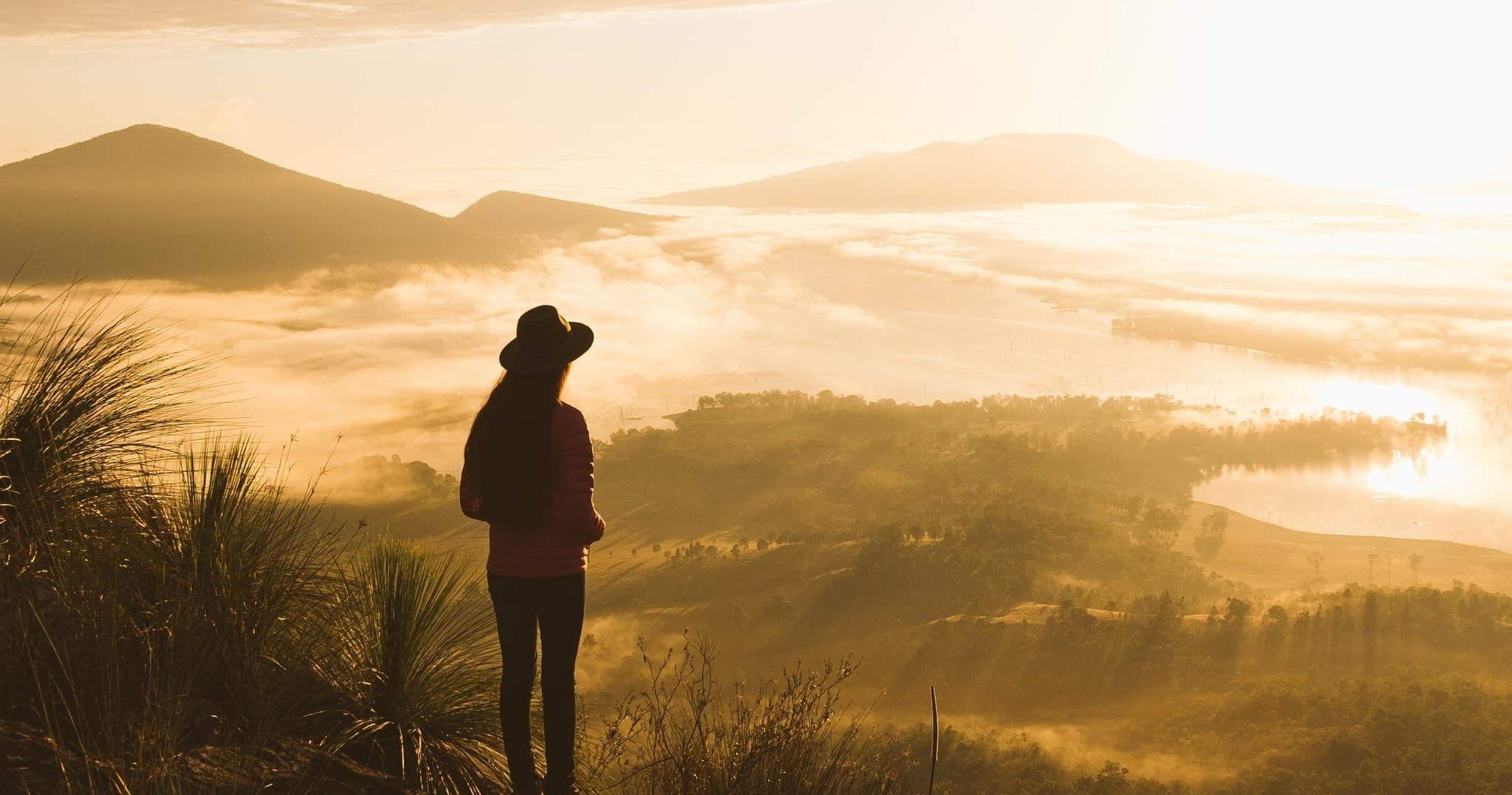 Person overlooking misty valley and hills at golden hour