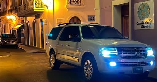 Nighttime city tour SUV with blue lights on cobblestone street
