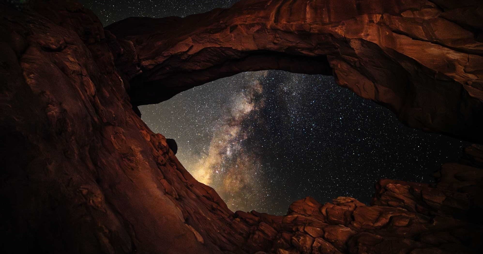 Panoramic red rock arch overlooking starry Milky Way in Moab