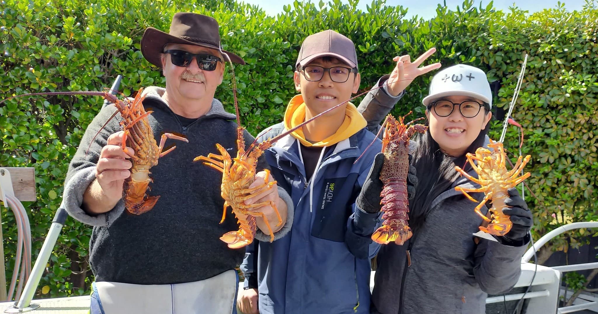 Three anglers displaying caught spiny lobsters dockside after trip