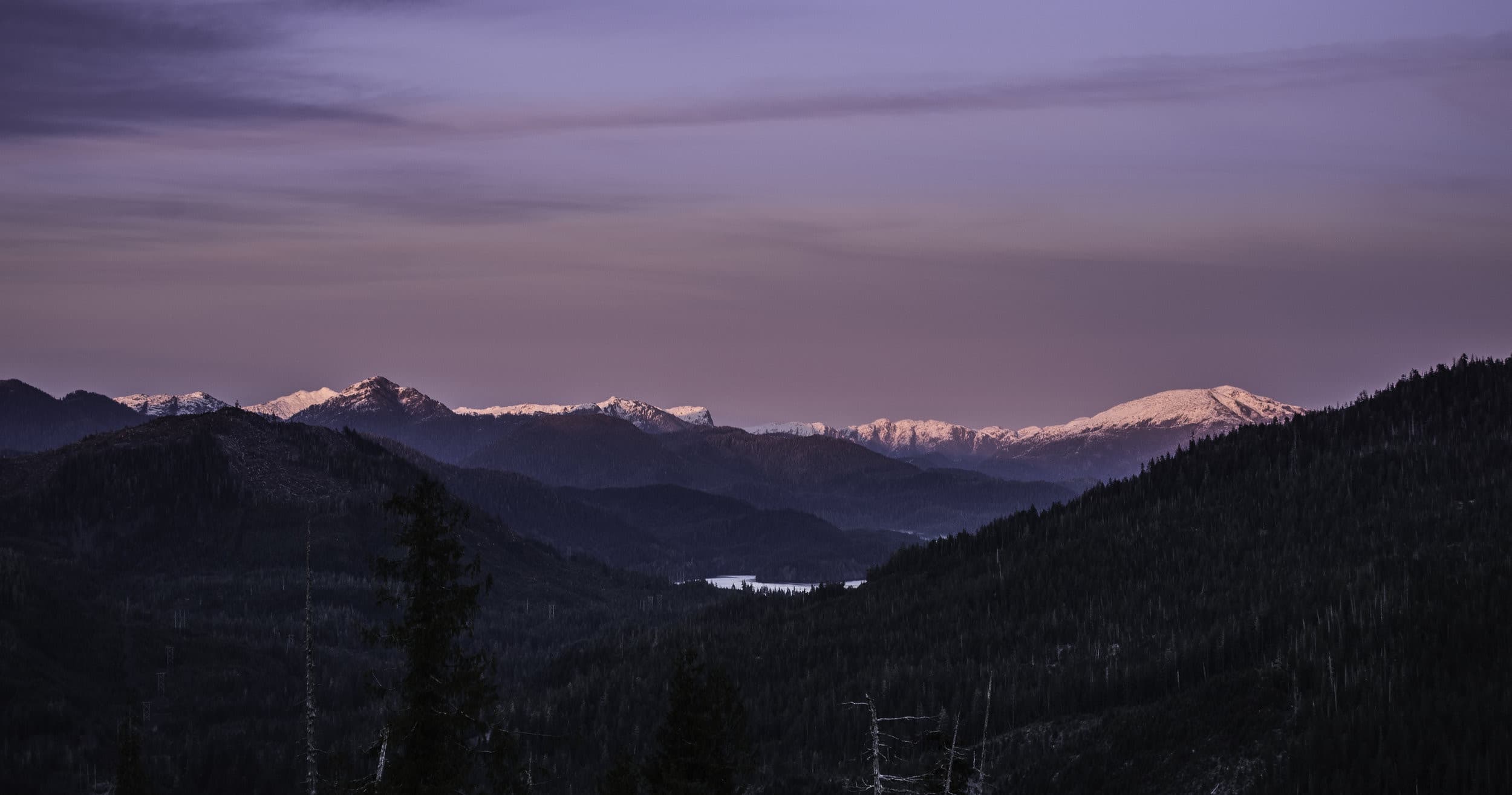 Panoramic mountain ridge at dusk with distant snowy peaks