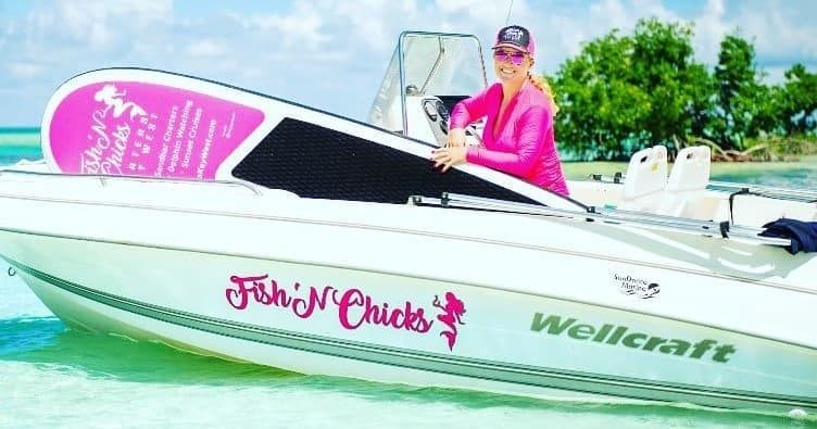 Fishing charter boat with Fishn'Chicks logo in shallow tropical waters