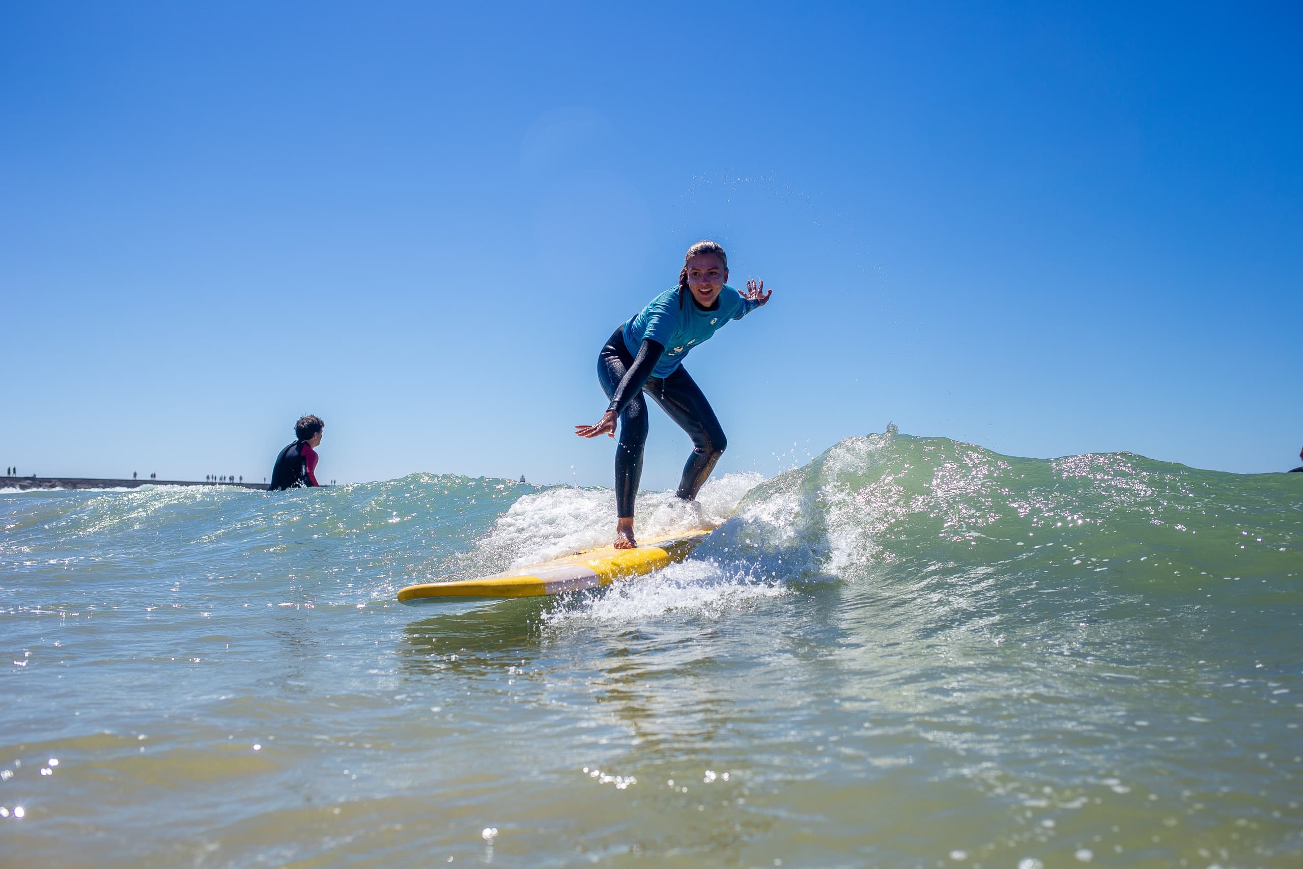 Surfer balancing on yellow board riding green ocean wave