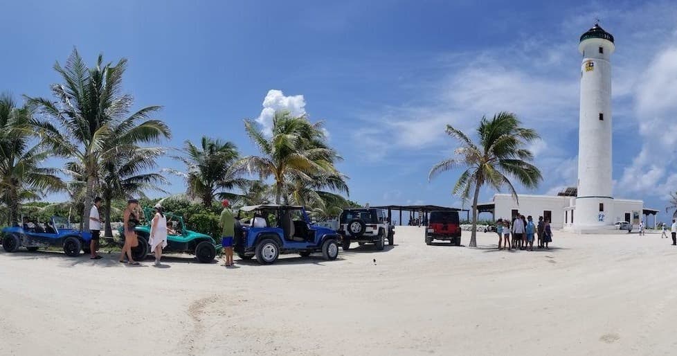 Beachside jeeps parked by lighthouse on sandy Cozumel shore