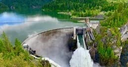 Hydroelectric dam spilling into green reservoir, scenic water infrastructure